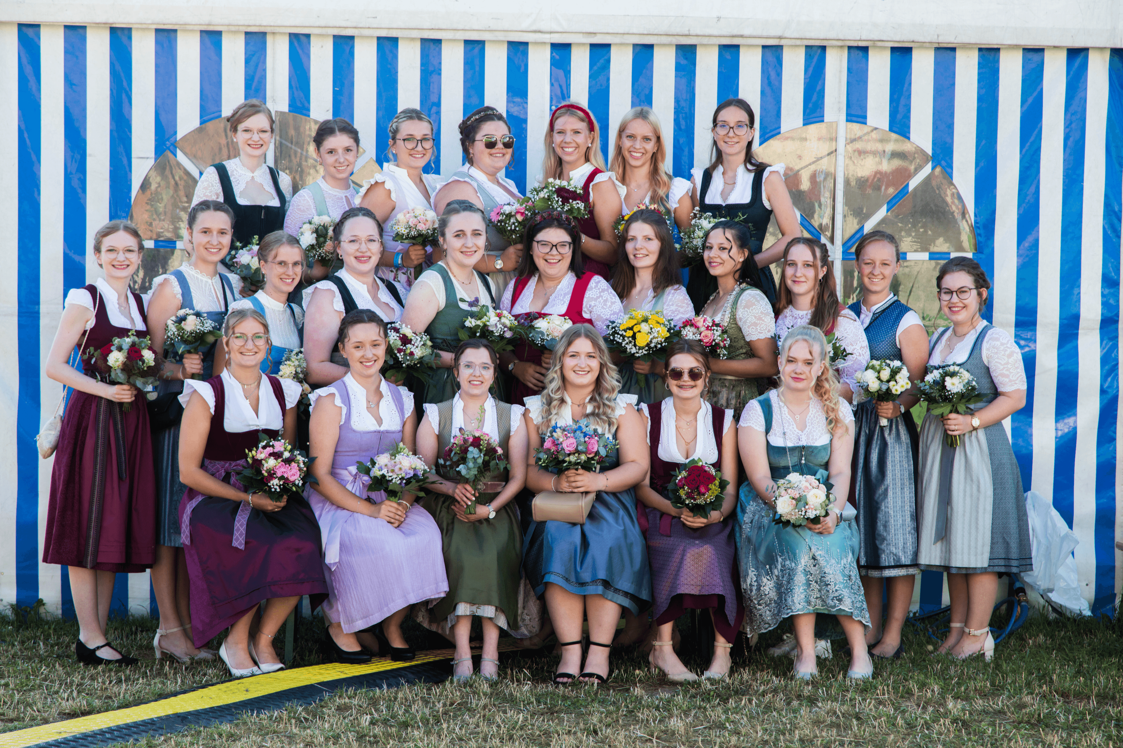 Gruppenfoto aller Festdamen mit Blumensträußen vor dem Festzelt