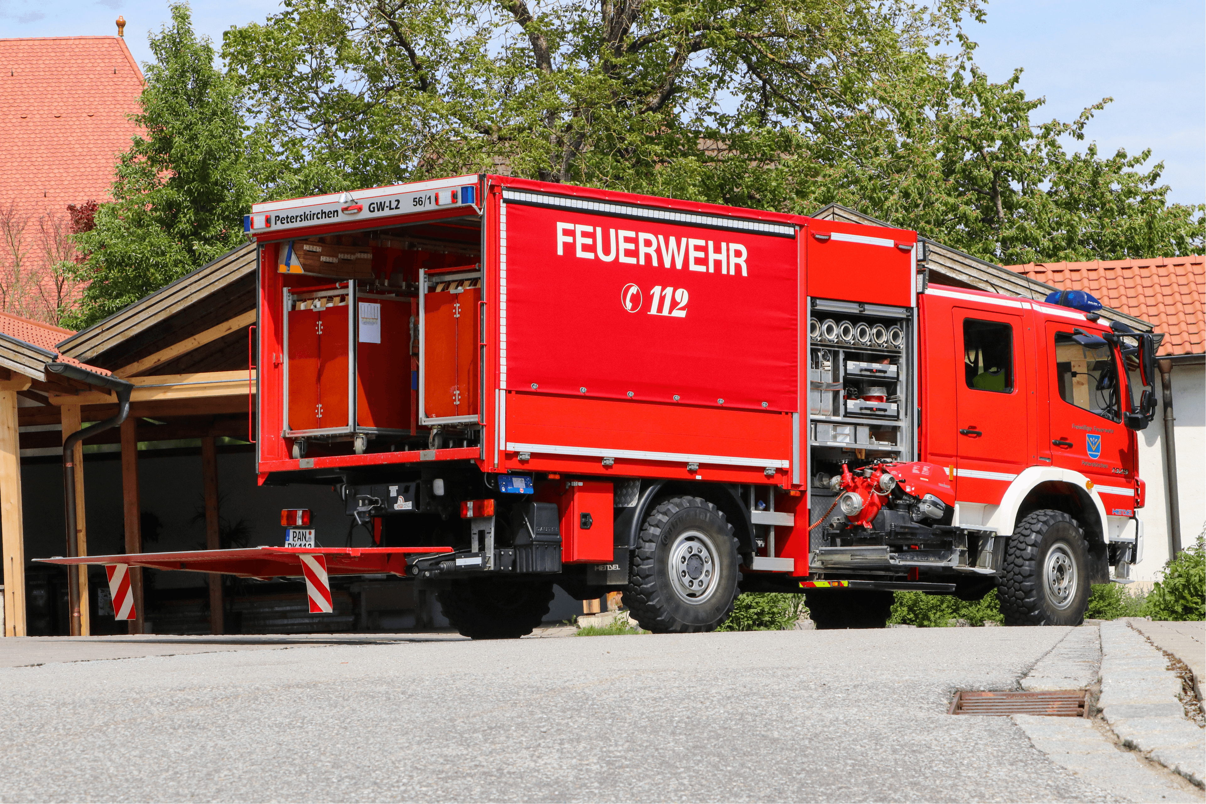 Gerätewagen von hinten vor dem Feuerwehrhaus, Kofferaufbau und Geräteräume geöffnet