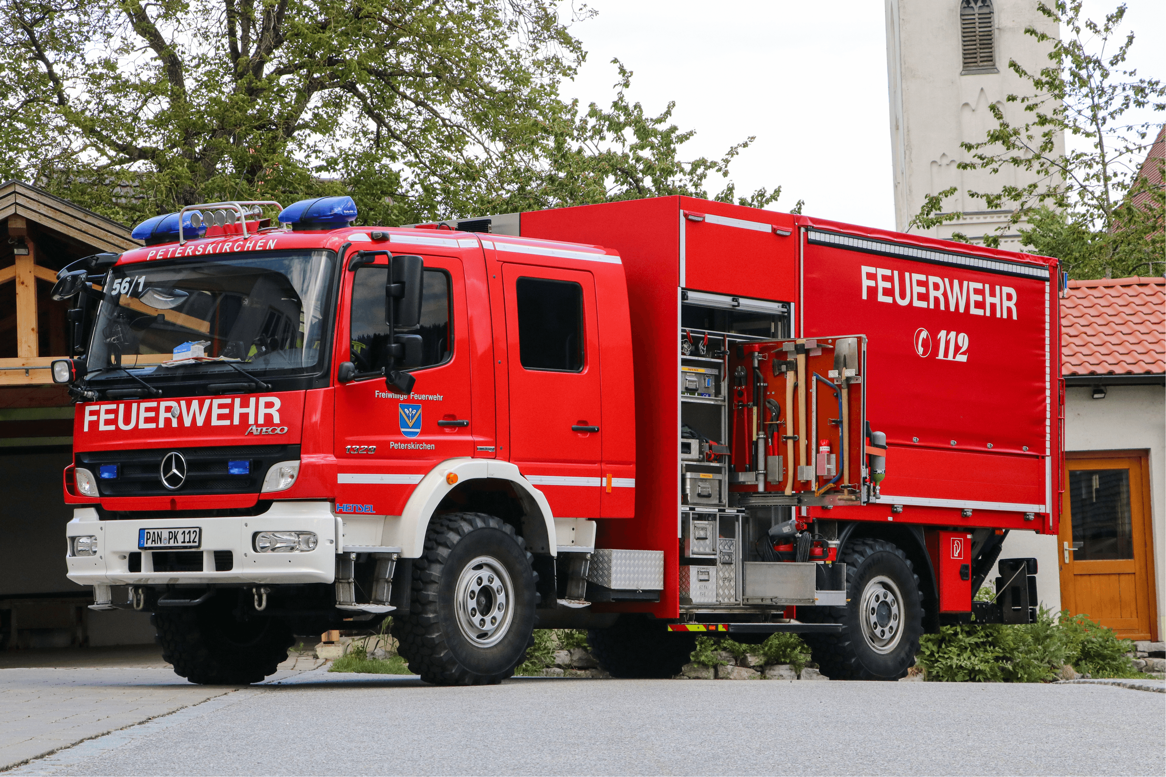 Gerätewagen von der Seite vor dem Feuerwehrhaus, im Hintergrund der Kirchturm von Peterskirchen
