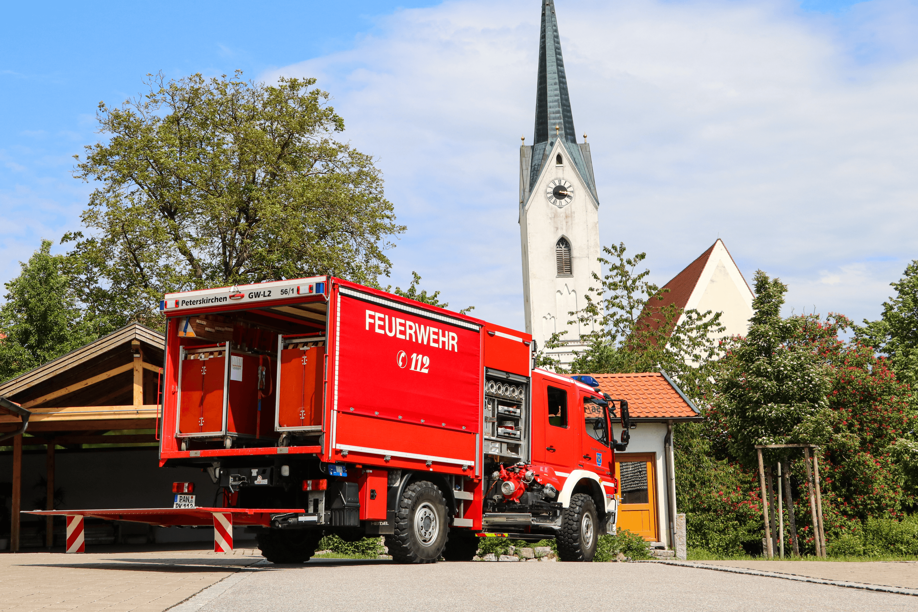 Gerätewagen Logistik (GW-L2) der Freiwilligen Feuerwehr Peterskirchen von hinten, im Hintergrund der Kirchturm von Peterskirchen