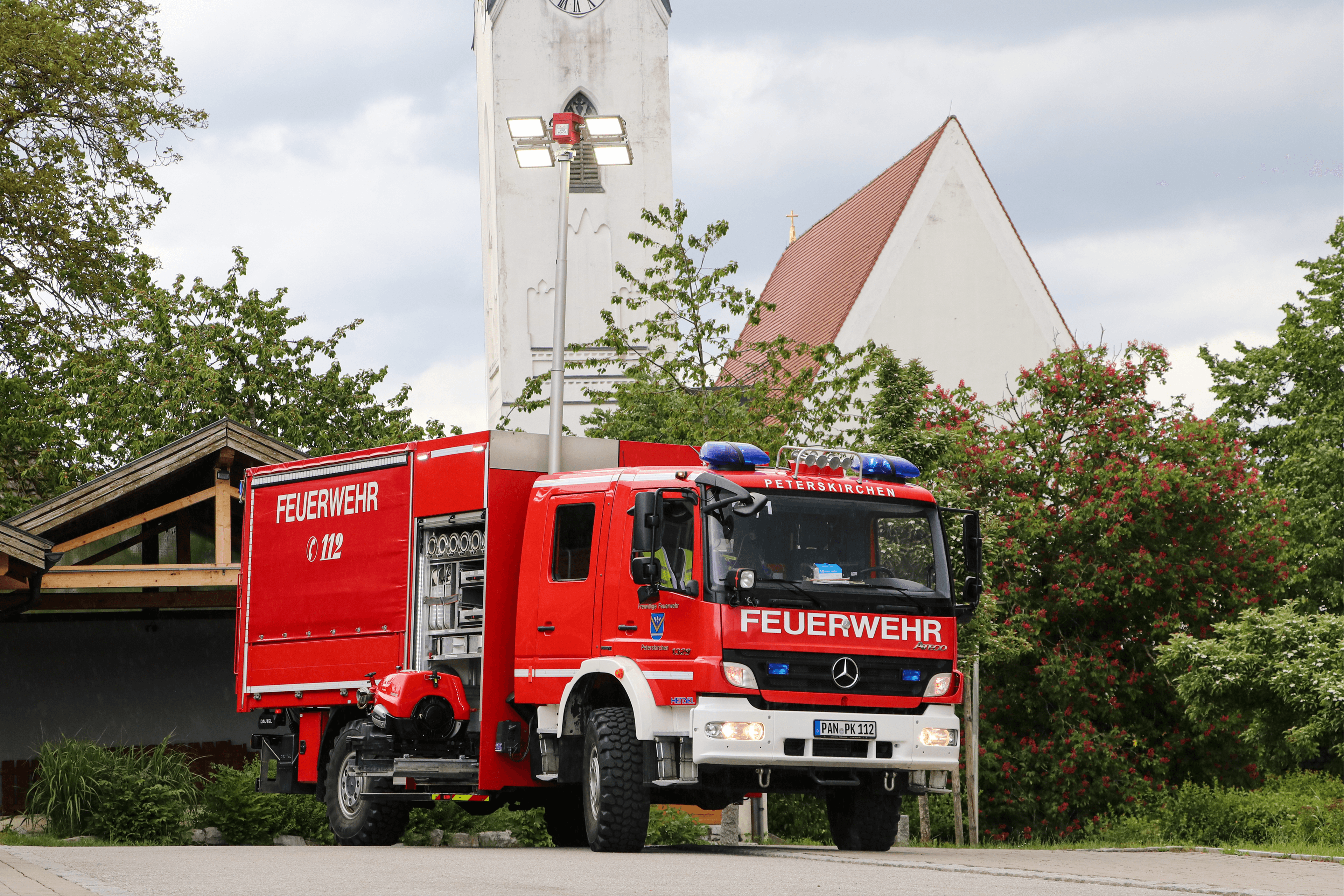 Gerätewagen Logistik (GW-L2) der Freiwilligen Feuerwehr Peterskirchen von hinten, im Hintergrund der Kirchturm von Peterskirchen